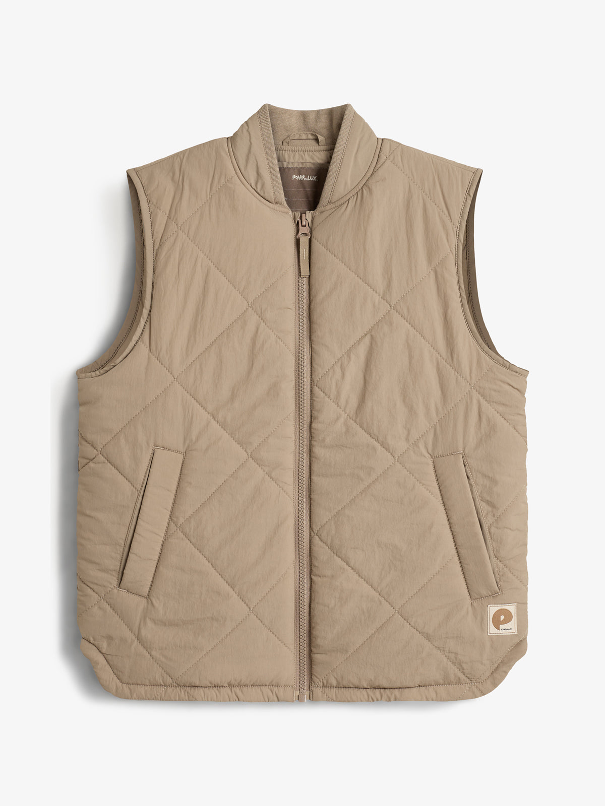 A tan quilted vest with a front zipper and two pockets is displayed on a plain white background. A small patch logo is visible on the lower right corner.