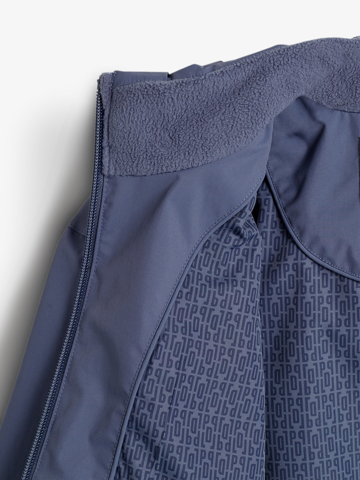 Eine dunkelblaue Jacke mit weichem, flauschigem Kragen und Reißverschluss ist teilweise geöffnet. Innenfutter zeigt blaues Muster mit dem Text "ODLO". Hintergrund ist weiß.