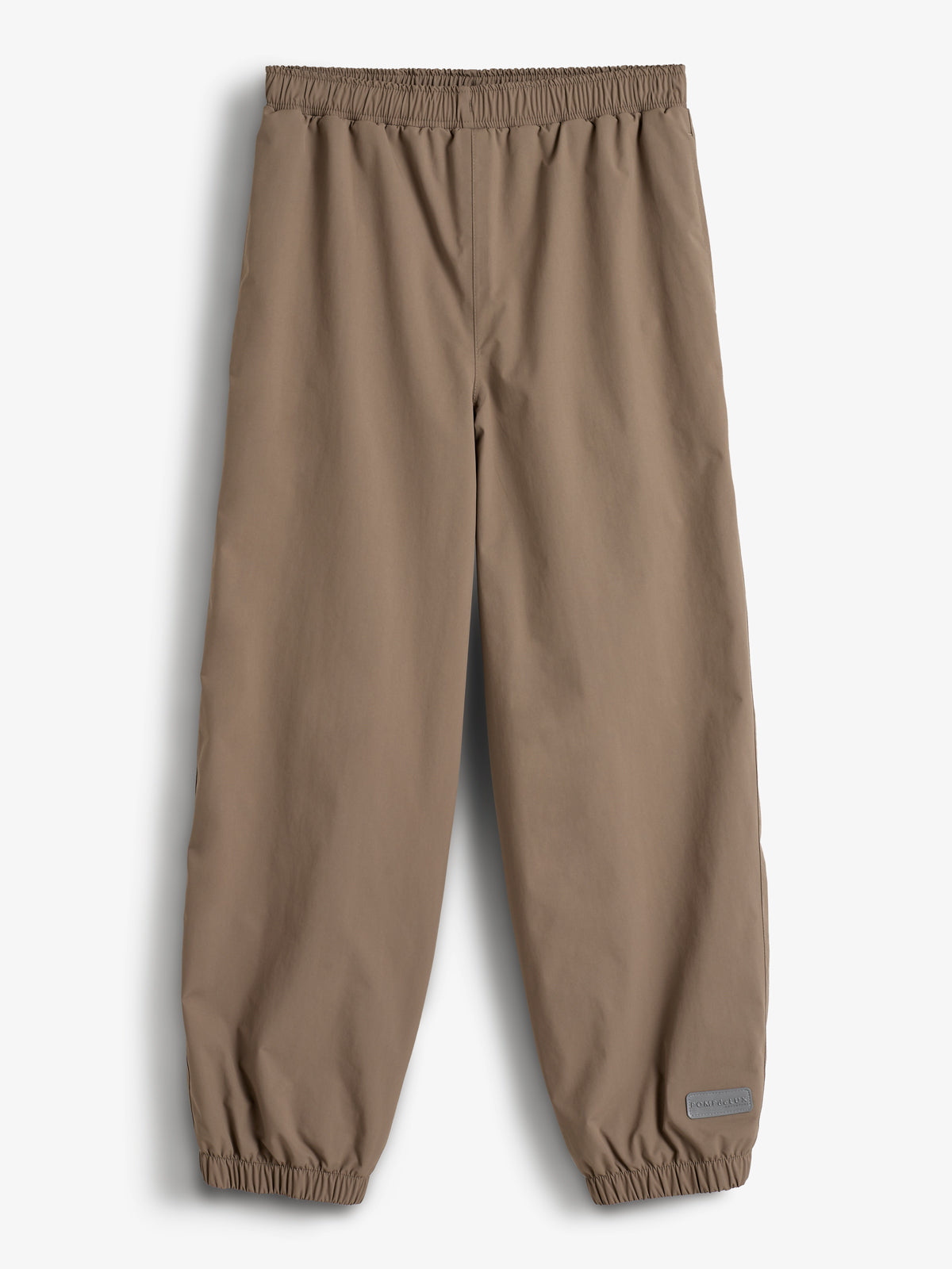 Eine beige Hose liegt flach auf einem weißen Hintergrund. Sie hat einen elastischen Bund und elastische Beinabschlüsse. Ein graues Etikett mit der Aufschrift "POLARN O.PYRET" befindet sich am Bein.