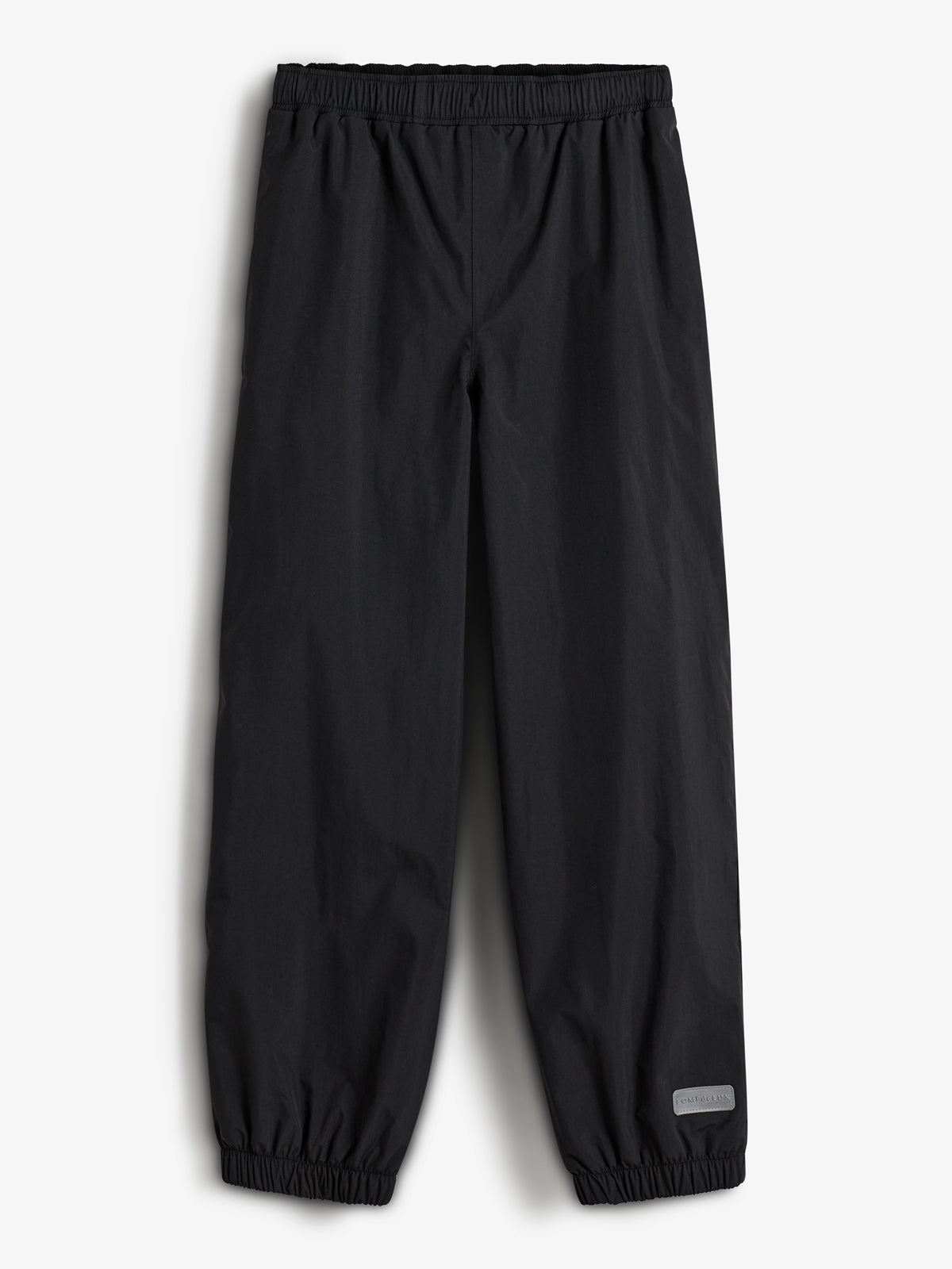 Eine schwarze Regenhose liegt flach. Sie hat einen elastischen Bund und Gummizüge an den Beinabschlüssen. Im unteren rechten Bereich befindet sich ein reflektierendes Etikett mit der Aufschrift "RAINWEAR".